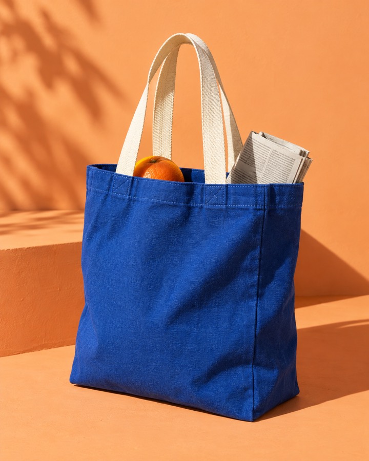 A blue Everyday Tote on an apricot backdrop